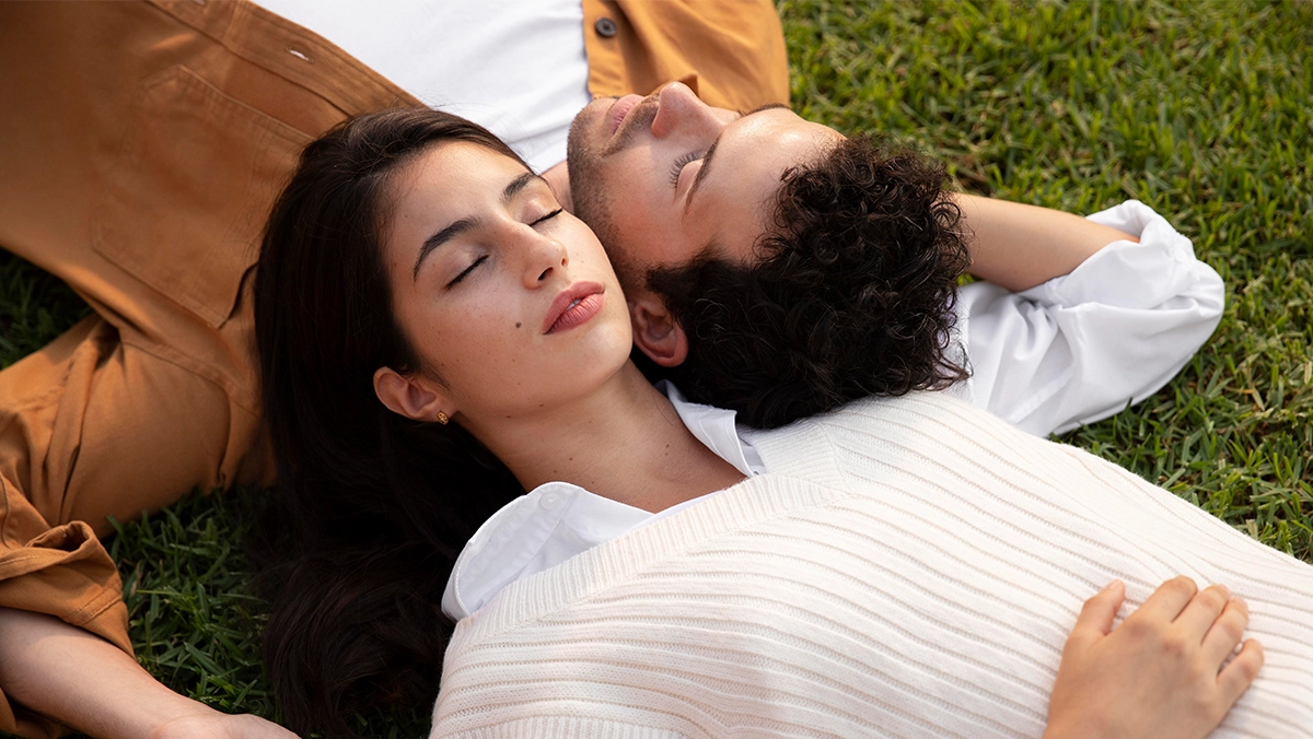 Couple lying on grass together.